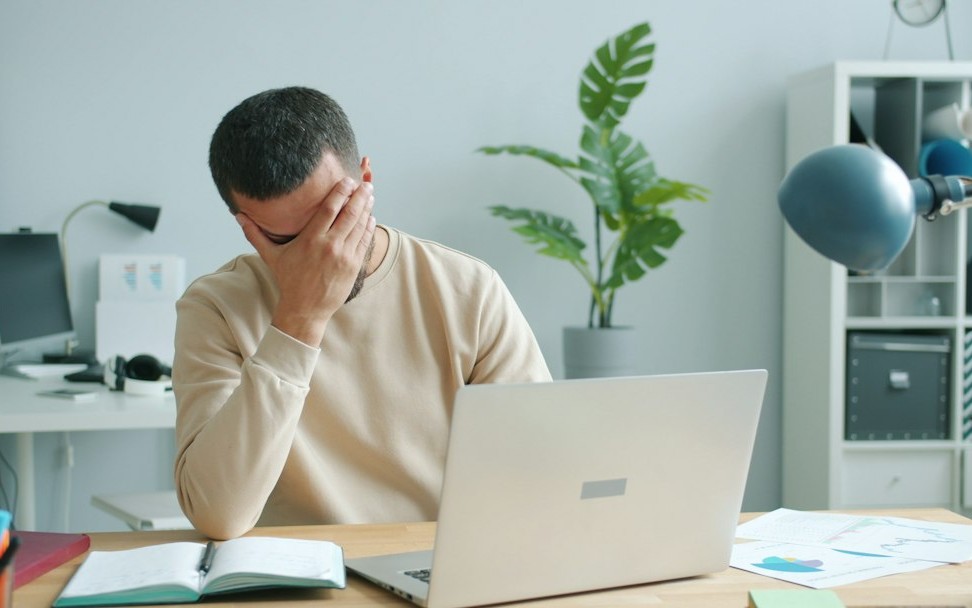 Man rubbing his face in front of laptop